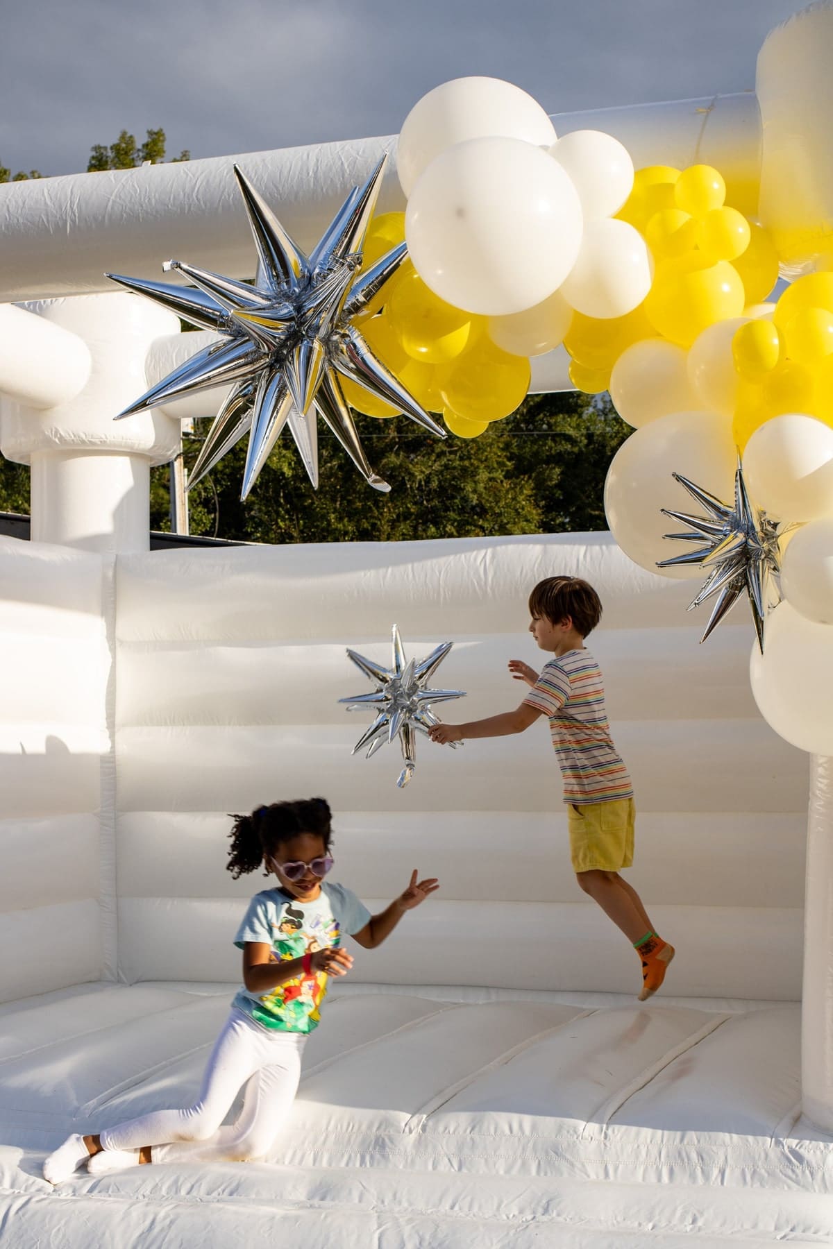 Kids jumping around a white bounce house